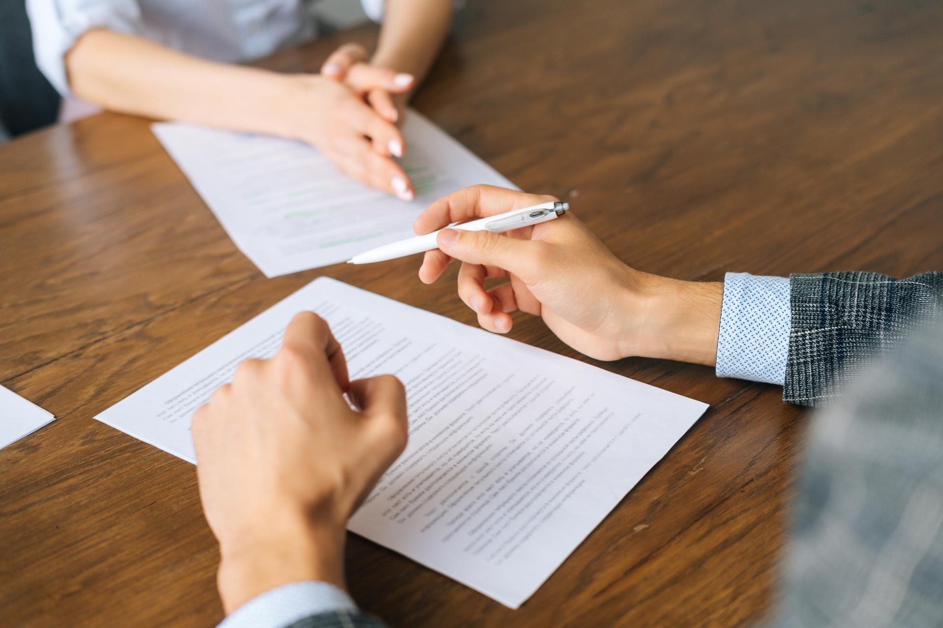 Close-up hands of unrecognizable businessman signing document holding pen, putting signature at official paper, subscribing name in statement with legal value